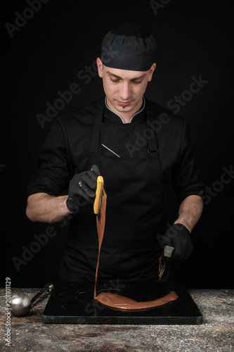 Chocolatier in black uniform in the process of making chocolates photo