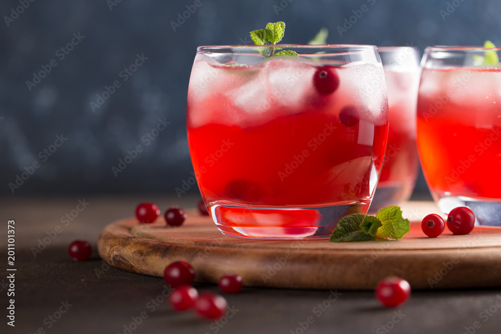 Vivid summer refreshing drink with cranberry, ice cubes and mint on the cutting board. Vivid summer refreshing drink with cranberry, ice cubes and mint on the cutting board.