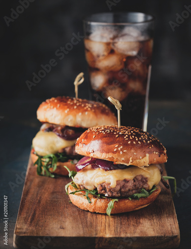 Street food, fast food. Homemade juicy burgers with beef, cheese and caramelized onions on the wooden table.
