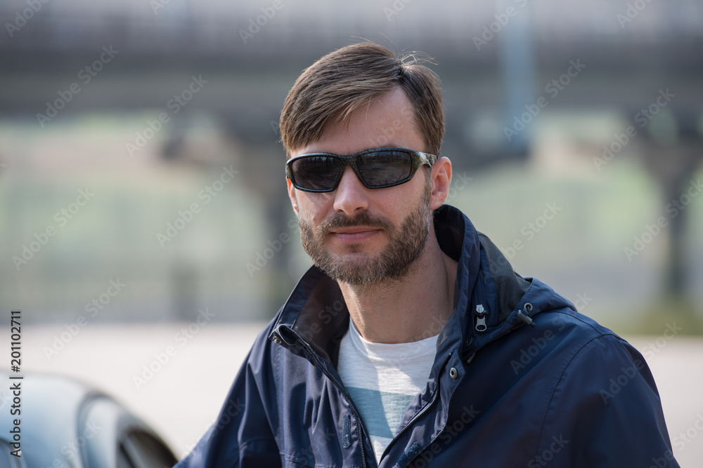 portrait of a bearded man wearing sunglasses in a park.