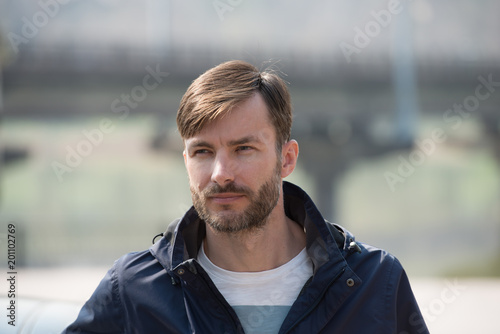 bearded man looks around in the city street.