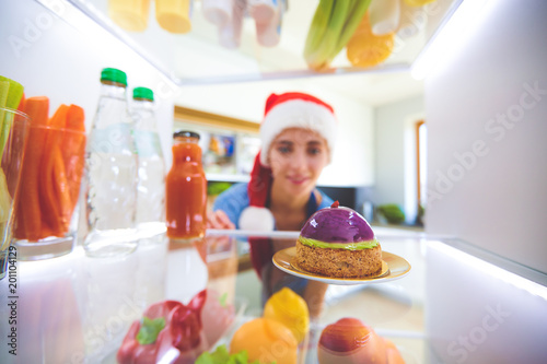 Portrait of female standing near open fridge full of healthy food  vegetables and fruits. Portrait of female