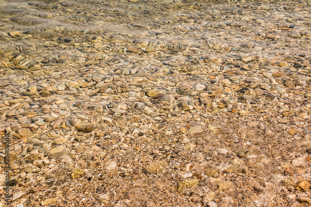 Yellow underwater peeble texture background.Small stones under the water surface.Various colorful wet pebbles texture as natural background.