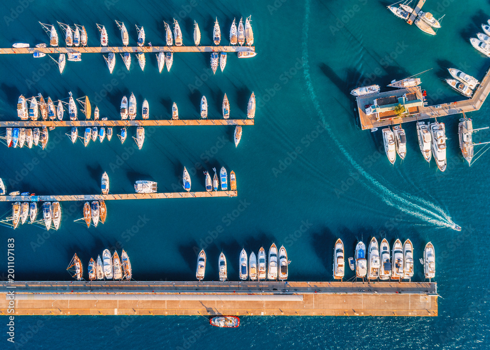 Aerial view of amazing boats at sunset. Minimalistic landscape with boats and sea in marina bay. Top view from drone of harbor with yacht, motorboat and sailboat. Beautiful port - obrazy, fototapety, plakaty 