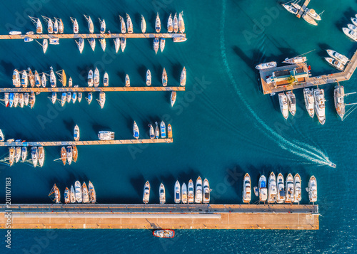 Aerial view of amazing boats at sunset. Minimalistic landscape with boats and sea in marina bay. Top view from drone of harbor with yacht, motorboat and sailboat. Beautiful port