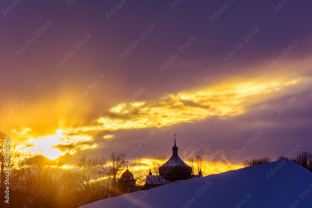 Silhouette of the church in the Ukrainian village at sunset in winter