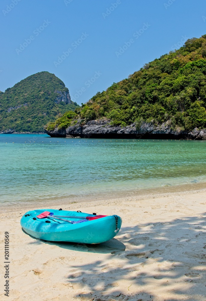 A turquoise kayak on a beach on the island of Ko Mae Ko (Angthong Marine National Park) in Thailand. This image can be used to represent adventure holiday activities. A turquoise kayak on a beach on the island of Ko Mae Ko (Angthong Marine National Park) in Thailand. This image can be used to represent adventure holiday activities.