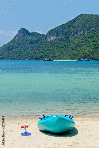 A turquoise kayak on a beach on the island of Ko Mae Ko (Angthong Marine National Park) in Thailand. This image can be used to represent adventure holiday activities. 