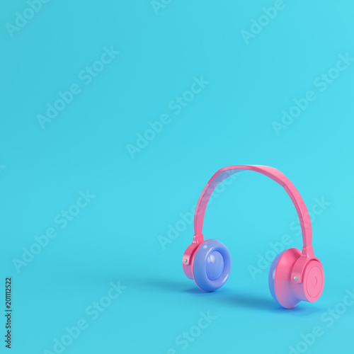 Pink headphones on bright blue background in pastel colors