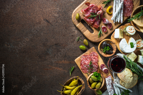 Foto Antipasto delicatessen - meat, cheese, olives and wine on stone