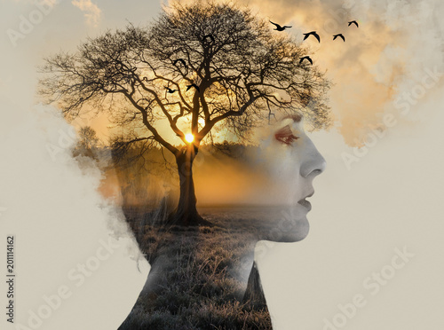 Konstfotografi double exposure, beautiful woman with tan fused with a sunset and a lonely tree,
