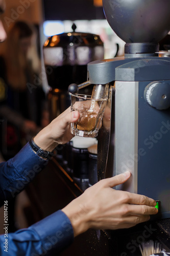 the barista s hand pours coffee out of the coffee machine glass beaker