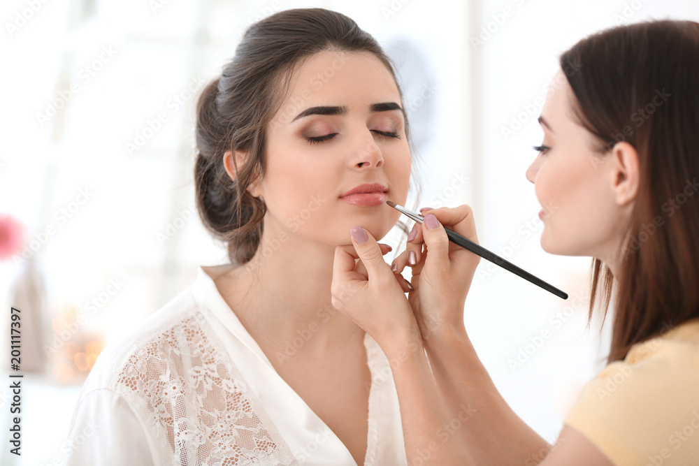 Professional makeup artist working with young woman in salon Professional makeup artist working with young woman in salon