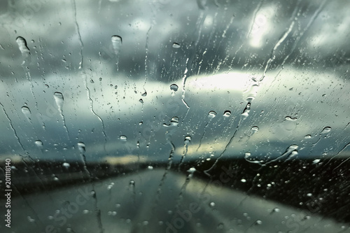 Rain drops on a car windshield. Rainy day view through a car window. Rainy season concept