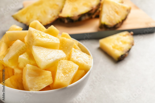 Bowl with fresh pineapple slices on grey background, closeup