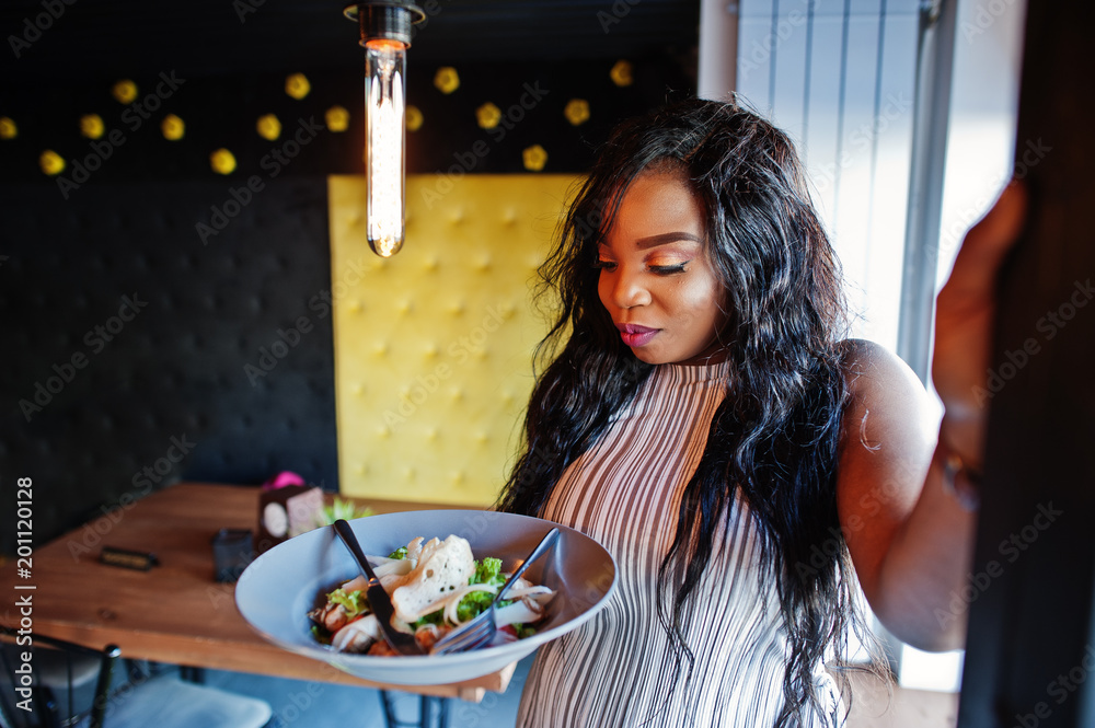 African american woman in cafe with plate of salad.