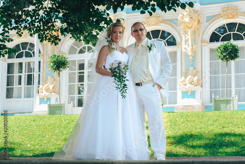 Wedding ceremony in nature.  Lovers newlyweds posing under a tree, both in white delicate clothes.