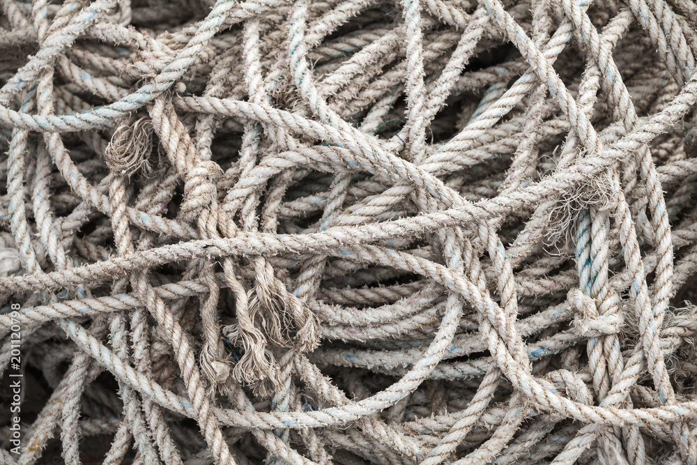Gray sea ropes lie in a heap in fishing port
