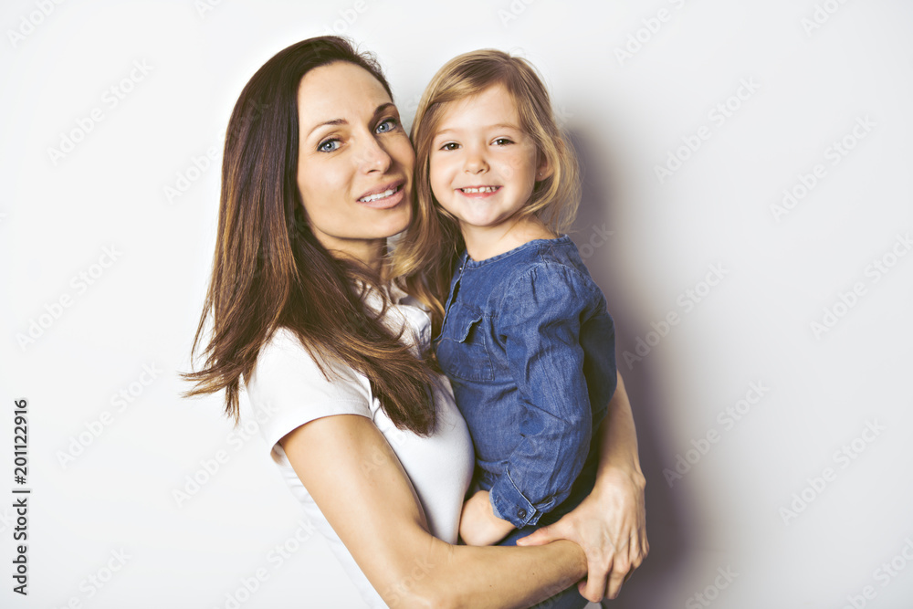 Beautiful young woman with her little cute daughter on white background.