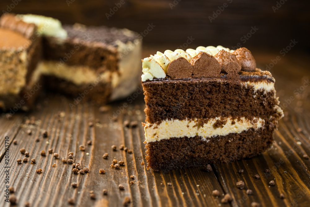 Dark chocolate vegan cake with candies and nuts on wooden background Dark chocolate vegan cake with candies and nuts on wooden background