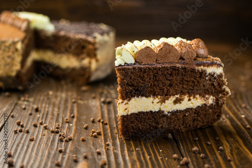 Dark chocolate vegan cake with candies and nuts on wooden background