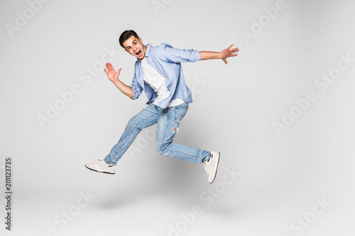 Smiling joyful man jumping on white background.