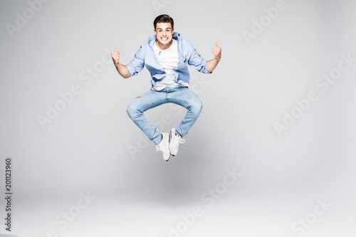 Happy man in shirt and jeans which jumping in studio over white background