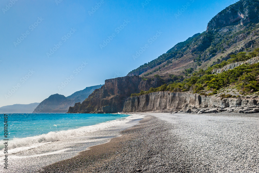 Crystal clear blue waters with fine pebbles in Domata beach at Sfakia in Crete, Greece. The beach is the ending point of the wild and rugged gorge of Klados