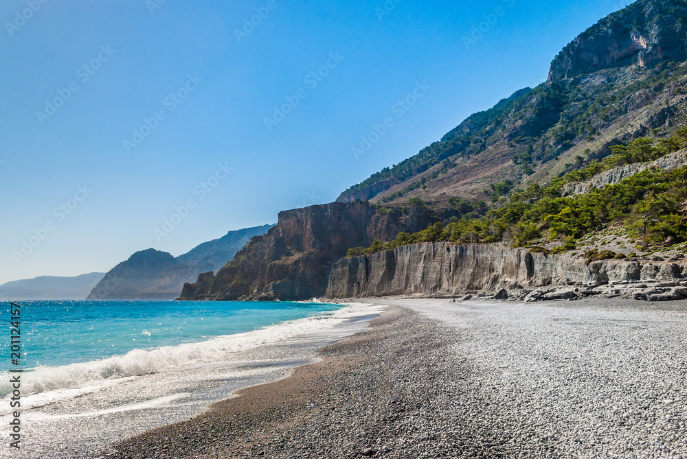 Crystal clear blue waters with fine pebbles in Domata beach at Sfakia in Crete, Greece. The beach is the ending point of the wild and rugged gorge of Klados Crystal clear blue waters with fine pebbles in Domata beach at Sfakia in Crete, Greece. The beach is the ending point of the wild and rugged gorge of Klados