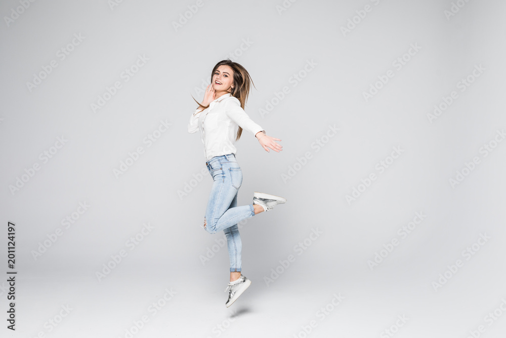 Joyful moments. Full length portrait of a young beautiful brunette girl jumping and smiling happily isolated on white background