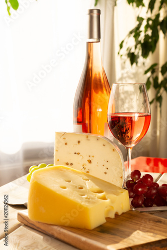 Dutch hard cheese Maasdam or Emmentaler, cheese with holes and white hard goat cheese with coriander served with rose wine