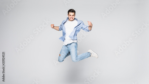 Photo Full-length photo of funny man in casual t-shirt and jeans running or jumping in