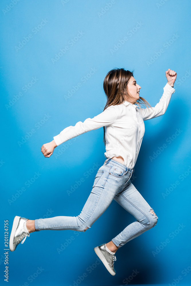 Successful young attractive laughing woman jumping up isolated on blue background