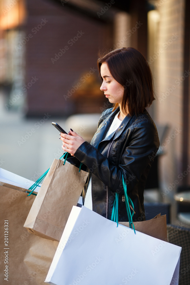Woman in leather jacket with many paper bags portrait