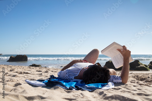 Man reading a book while lying on towel