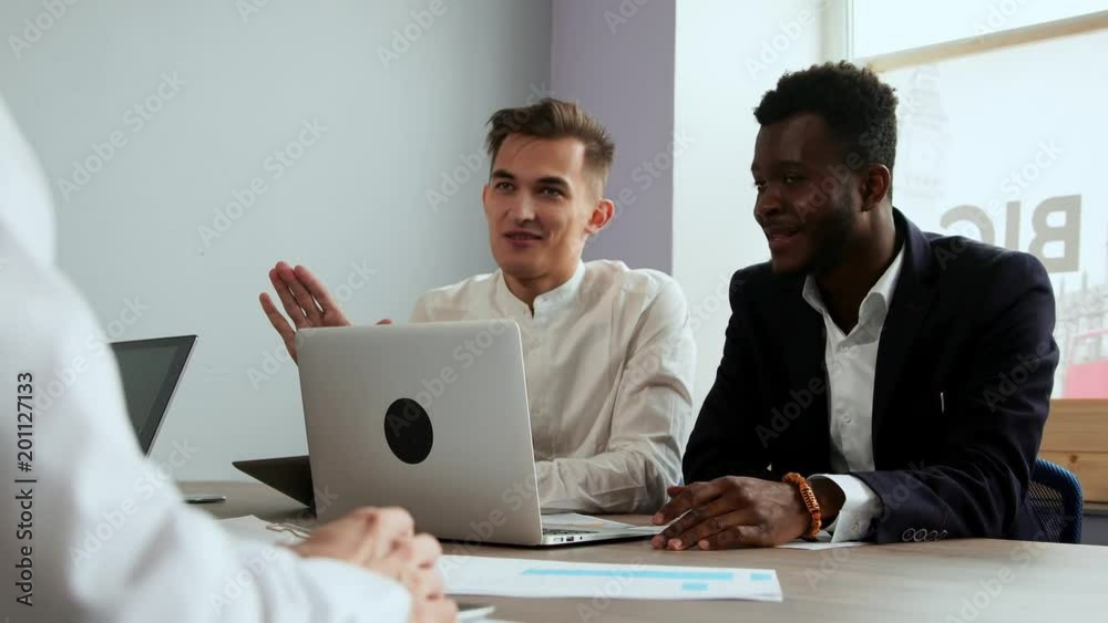 Modern office workers sitting at a laptop solve creative tasks to create new business products. Multi-ethnic groups of men and women Modern office workers sitting at a laptop solve creative tasks to create new business products. Multi-ethnic groups of men and women