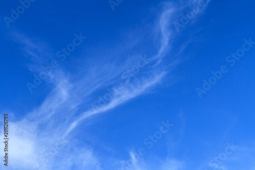 Bodies of unique delicate painterly diffused thin white cloud patterns on a blue sky nature background