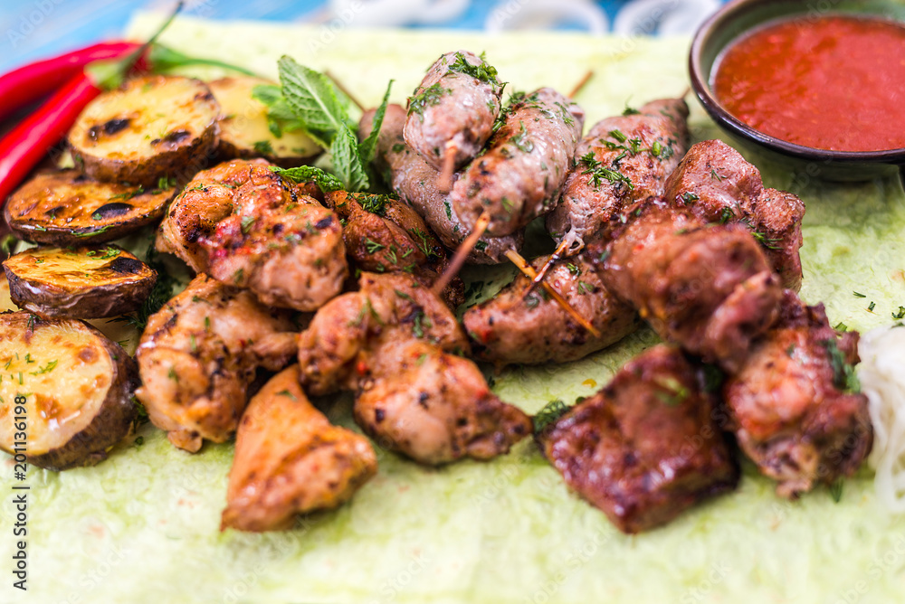 shish kebabs with vegetables and herbs on a pita bread sheet