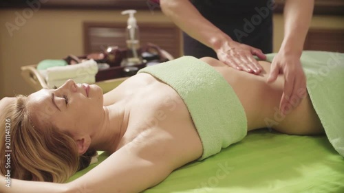 Professional massage therapist doing chinese massage of a woman's abdomen in spa salon