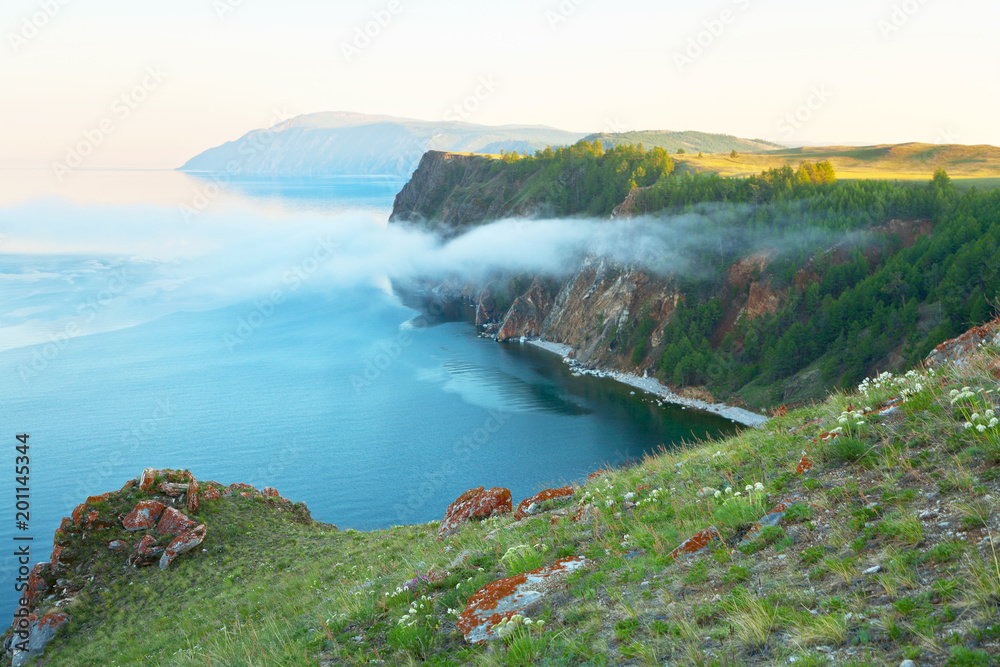 Beautiful summer landscape with a June fog over Lake Baikal at sunset