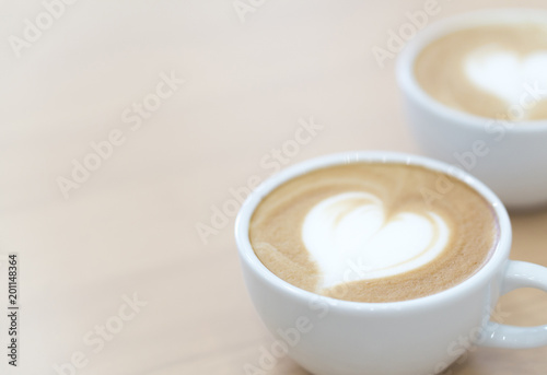 Closeup latte art coffee with heart shape in white cup for relax time and holiday concept, selective and soft focus