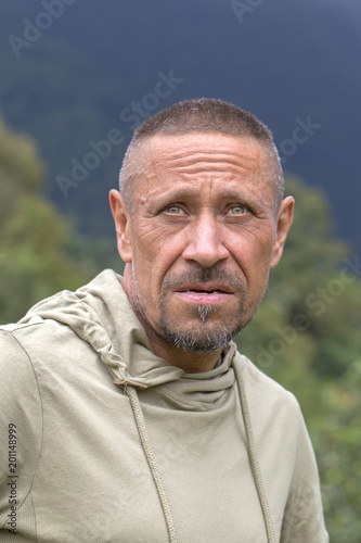 People and lifestyle concept. Happy middle-aged unshaven man outdoor against green nature background, portrait close up