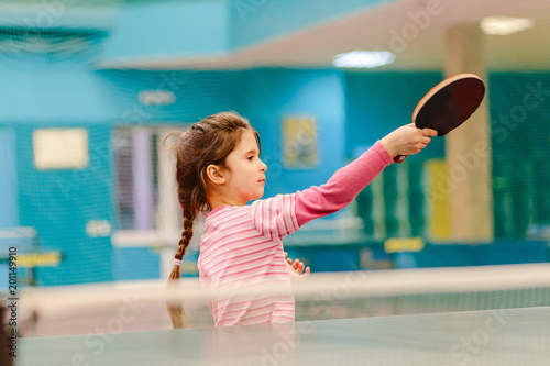 little girl playing table tennis in the tennis hall