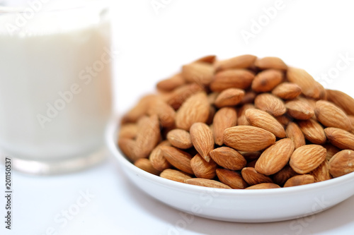 Almond milk in glass with almonds on white background