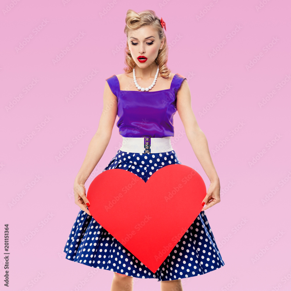 smiling woman holding heart symbol, dressed in pin-up style smiling woman holding heart symbol, dressed in pin-up style