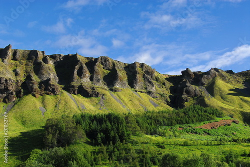 Iceland. Sunny morning with mountains  covered green grass and blue sky