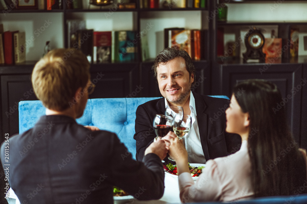 Three businesspeople sitting at restaurant and talking about business projects.