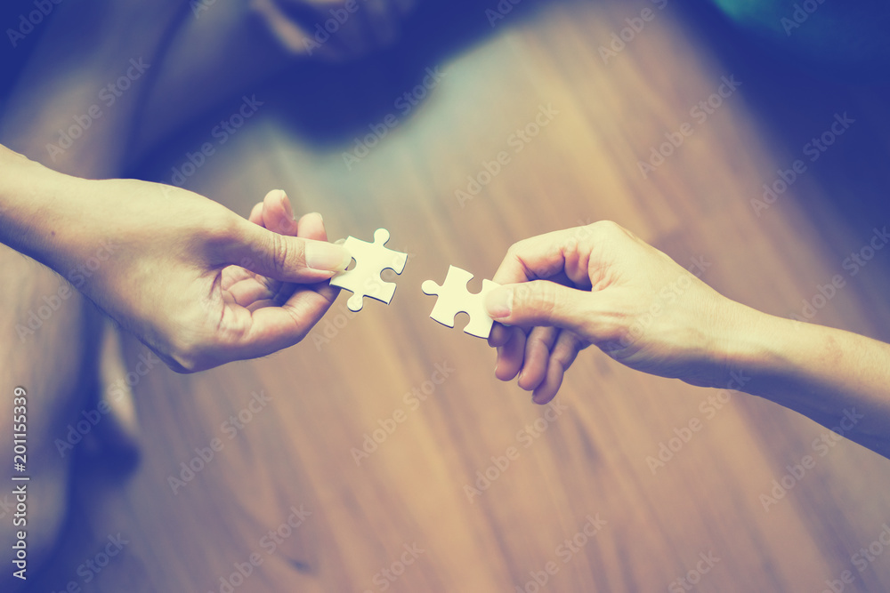 two hands trying to connect couple puzzle piece  Jigsaw alone wooden puzzle Teamwork, partnership, business idea, cooperation management concept - obrazy, fototapety, plakaty 