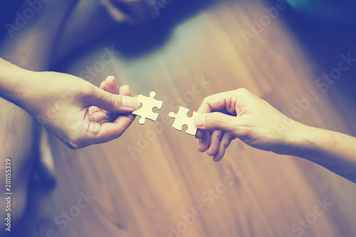 two hands trying to connect couple puzzle piece  Jigsaw alone wooden puzzle Teamwork, partnership, business idea, cooperation management concept photo