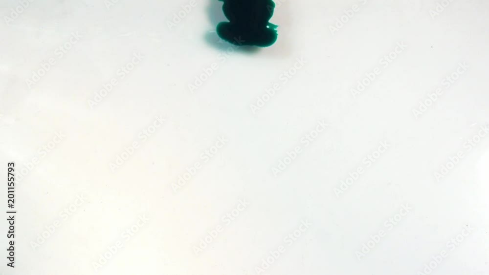Drop of green ink flows down on glass. Ink spread on a white background. Close-up view of flow of ink. Template for video and motion graphics Drop of green ink flows down on glass. Ink spread on a white background. Close-up view of flow of ink. Template for video and motion graphics
